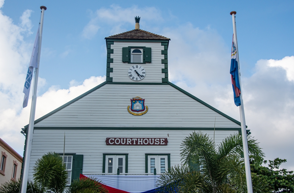 A white building marked courthouse with two country flags on flagpoles outside