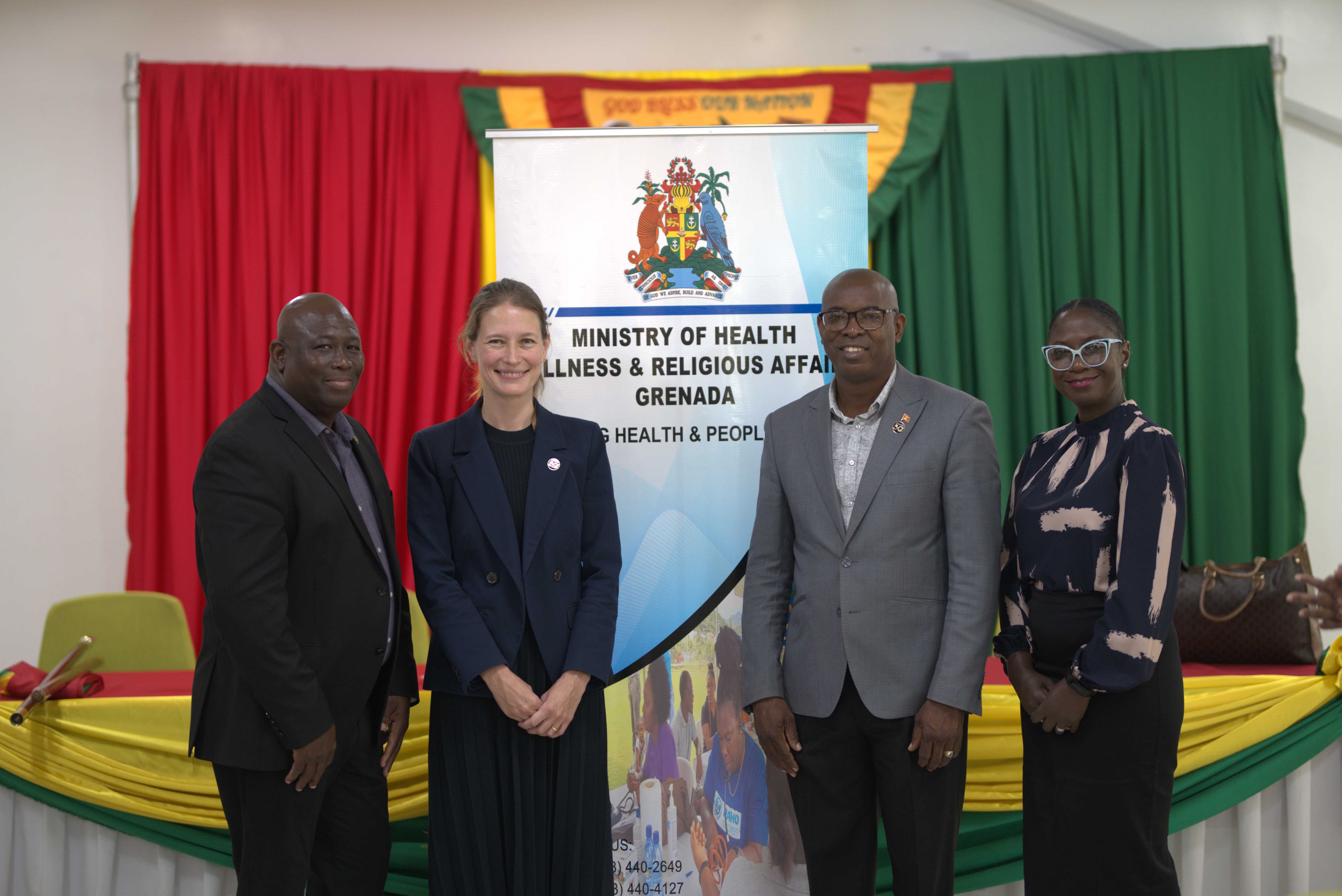 Four people standing in front of a multi-coloured banner