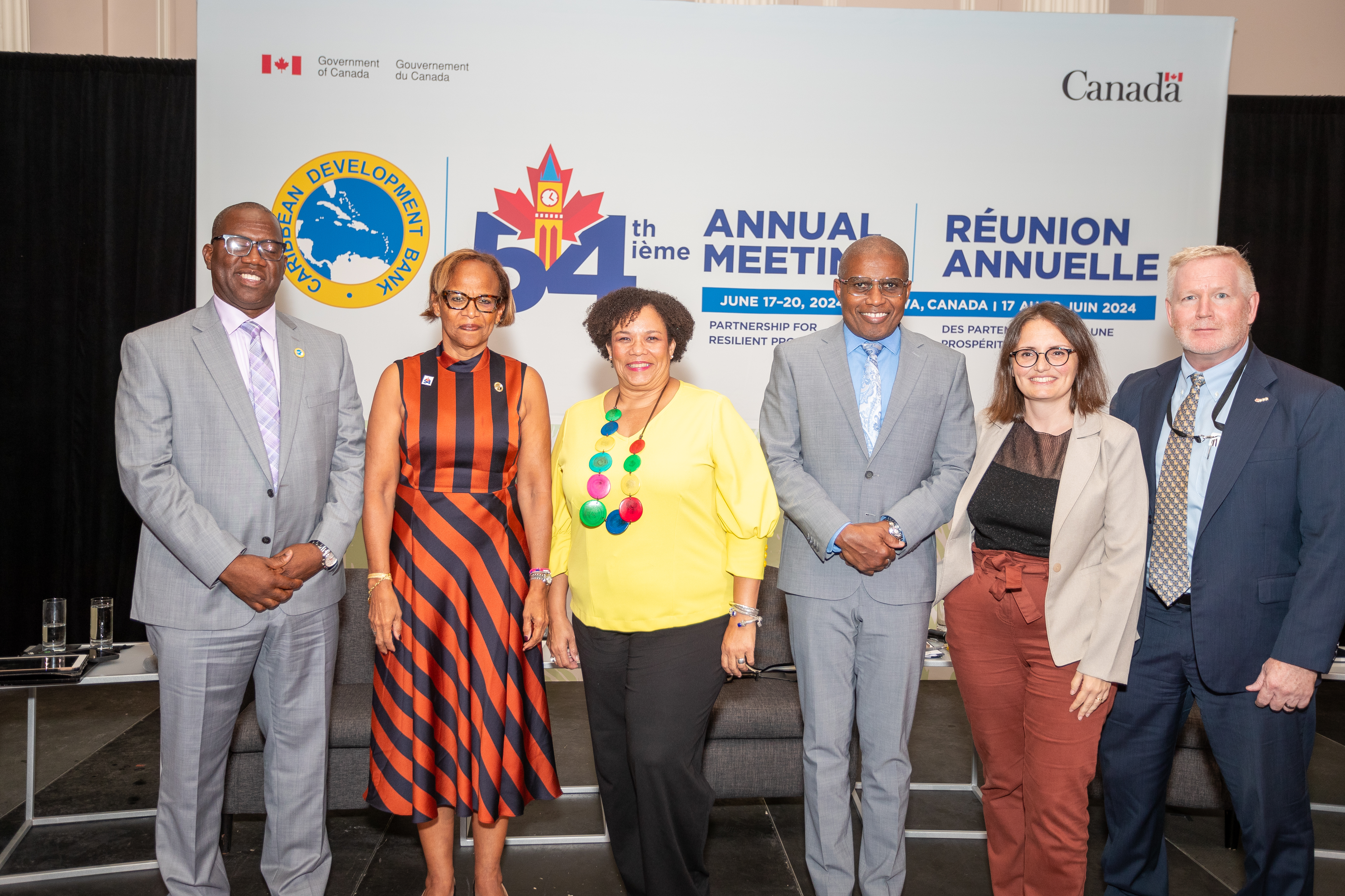 Six people, three men and three women are standing on a platform with a CDB backdrop behind them.