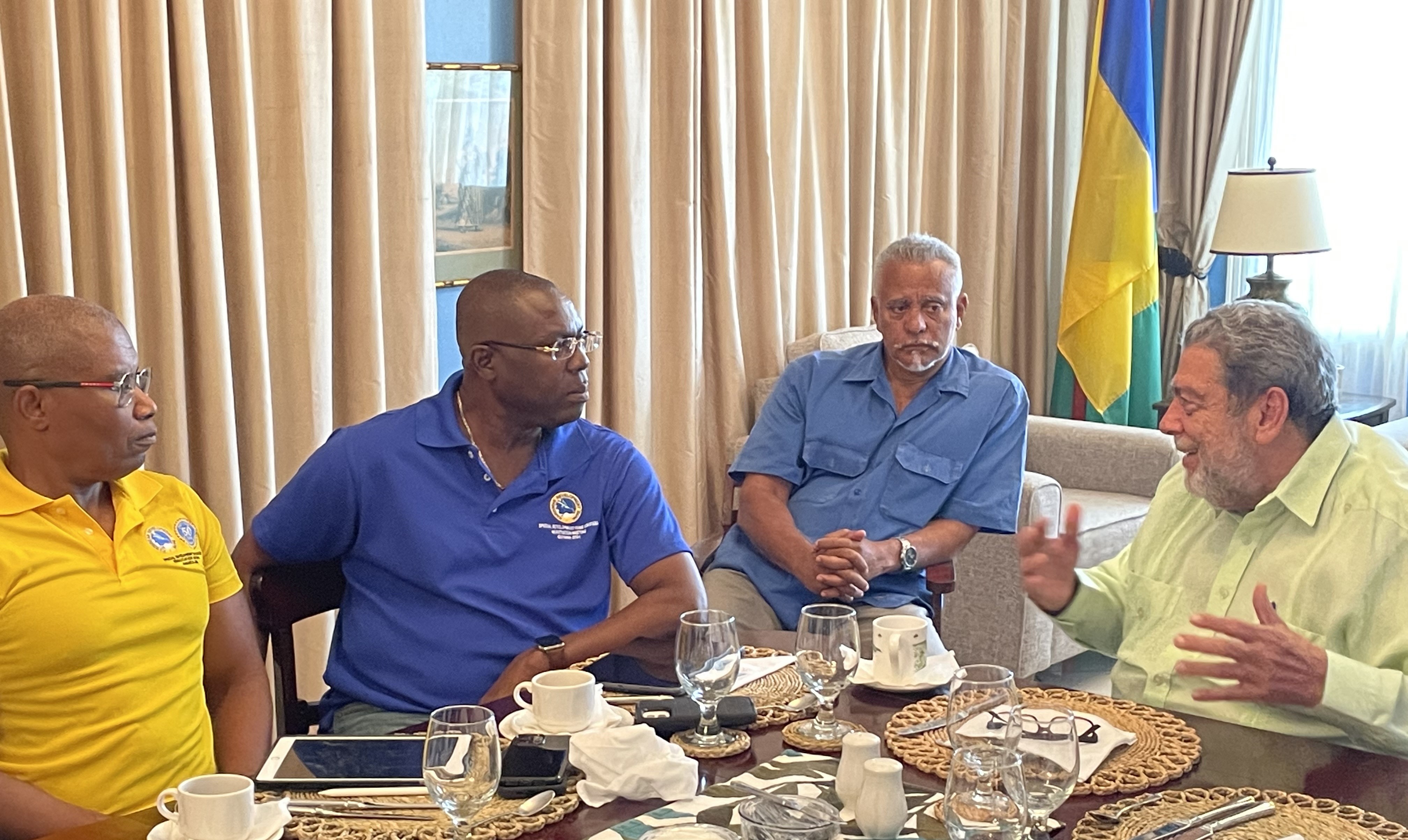 four gentlemen sit facing each other having a discussion