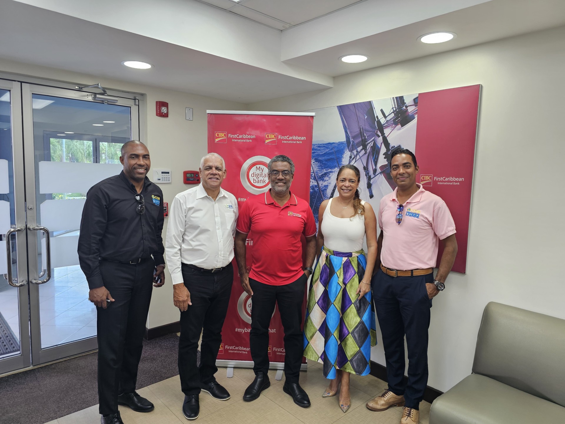 Partnerships are the core of discussions as the BNTF team shares a photo opportunity with Mr. Nigel Ollivierre, Country Head of the CIBC First Caribbean International Bank (centre in red). From left are Brandon Antoine, Deputy Project Manager of the Saint Lucia Social Development Fund, George Yearwood, Portfolio Manager of the BNTF Programme, Samantha Chantrelle, Strategic Partnership Consultant with the BNTF and Edrea Marques, Operations Officer (BNTF).