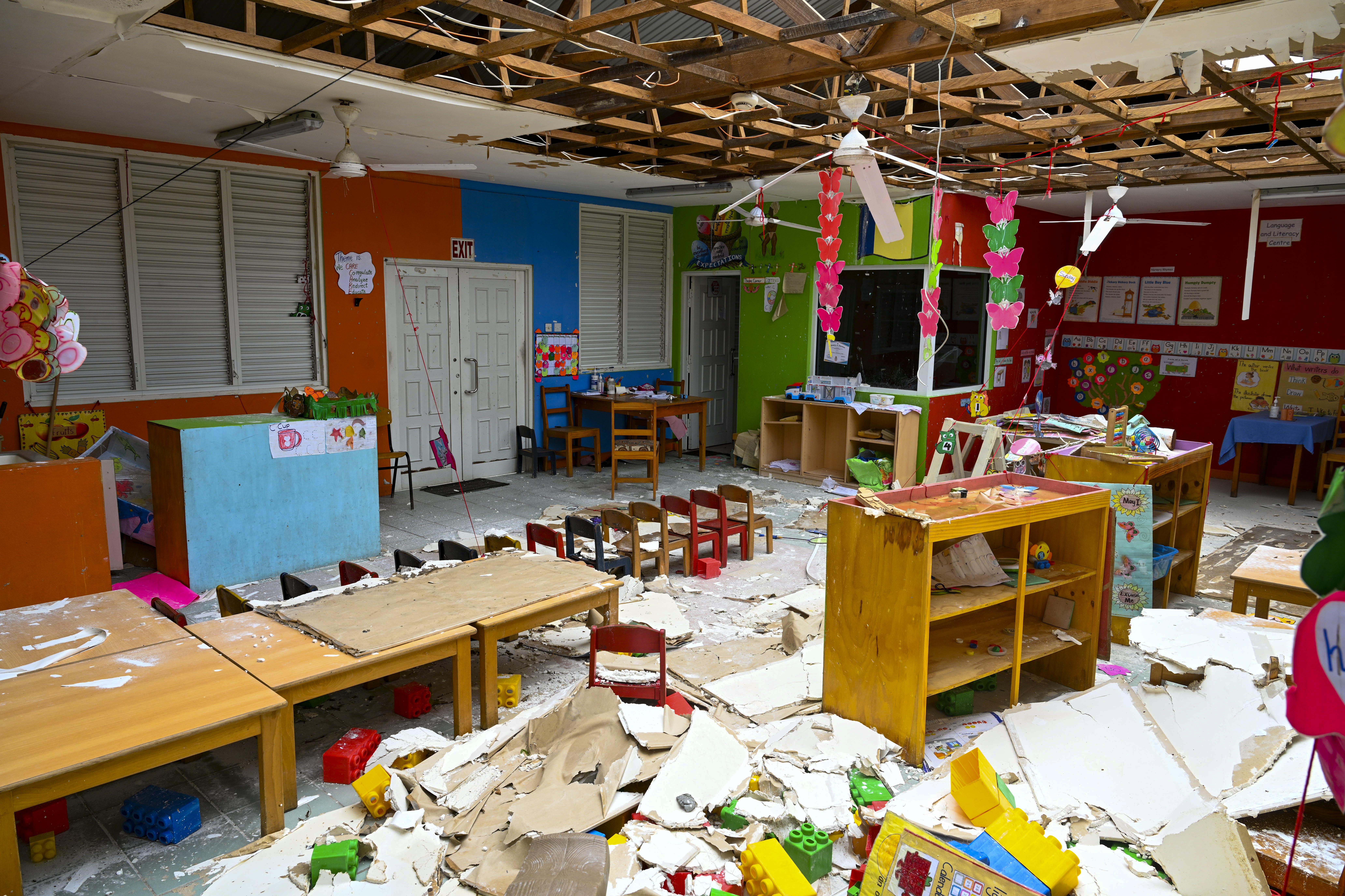 classroom with ceiling tiles on the floor and water damgaed school equipment