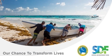 five men on a Caribbean beach pushing a small fishing boat into the water
