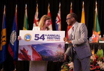 man handing over large signage board to woman on stage