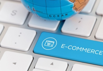 shot of globe on white keyboard with blue key marked e-commerce