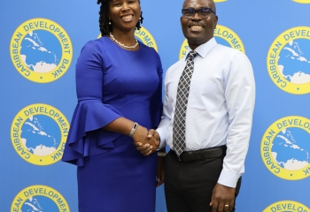 Lady in blue dress and man in white shirt black pants and tie standing shaking hands