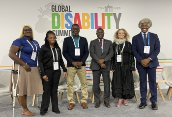 a group of abled bodied and disabled standing together in business attire in room 