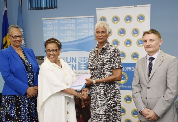 group photo of three females and one male standing in front of CDB and UN Women branded banners